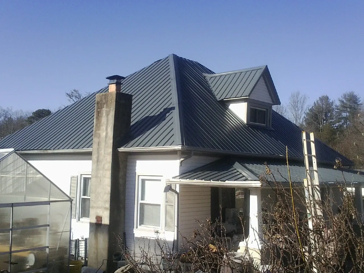 Dark blue standing seam metal roof on a white farmhouse with dormer — Slate & Tile Roof Repair by Roofing Brothers in Charlotte Hall