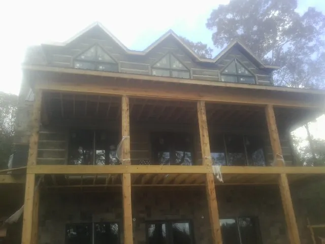 Dormers and porch framing on a large log home under construction — Roof Coating work by our crew in Charlotte Hall