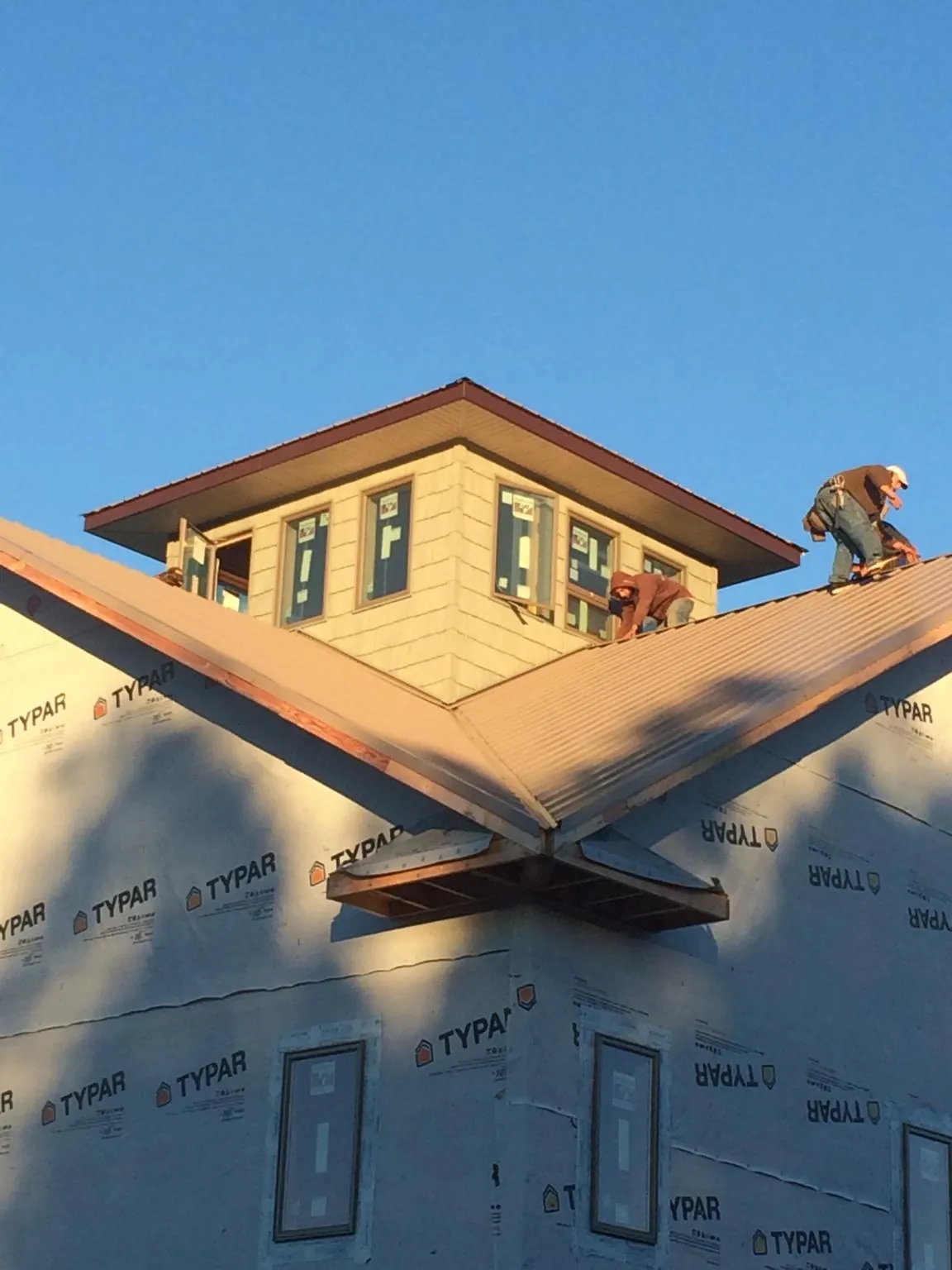 Roofers working around a rooftop cupola on a new metal roof at sunset — Roof Waterproofing in Charlotte Hall by Roofing Brothers